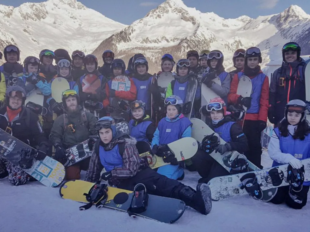 Große Gruppe sitzt für ein Foto im Schnee.